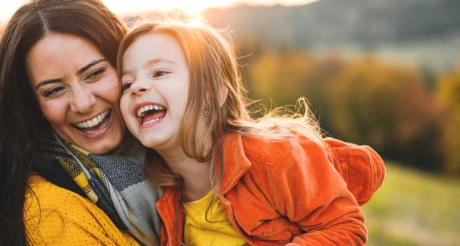 Une femme et sa fille l'air heureuse assises dans un champ