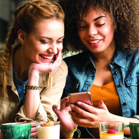 2 jeunes femmes rient en buvant un café