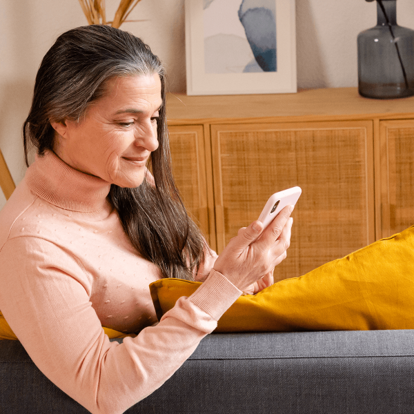 Femme consultant son mobile assise dans son salon