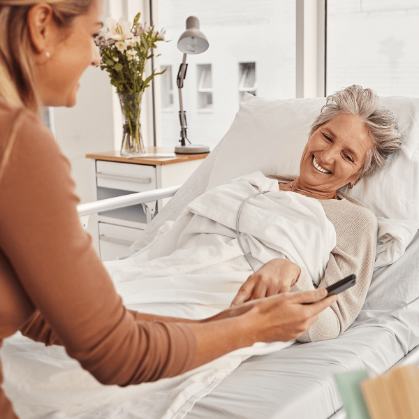Femme alitée dans une chambre d'hopital parlant avec une visiteuse