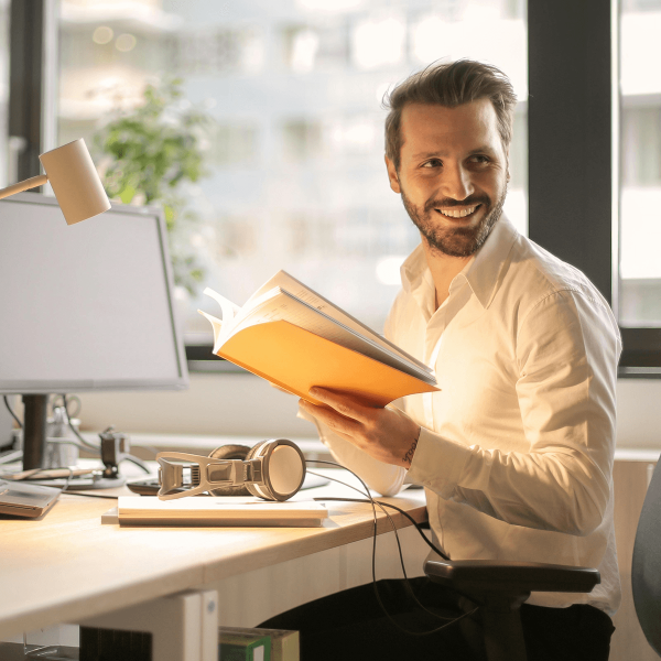 Homme à son bureau tenant un livre