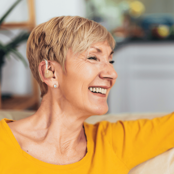 Femme souriante portant une aide auditive