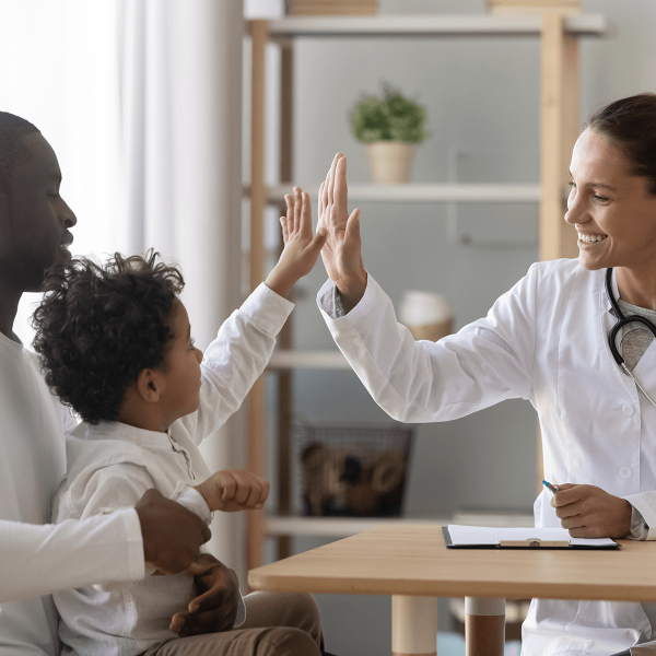 Pediatre tapant dans la main d'un enfant en consultation avec son père