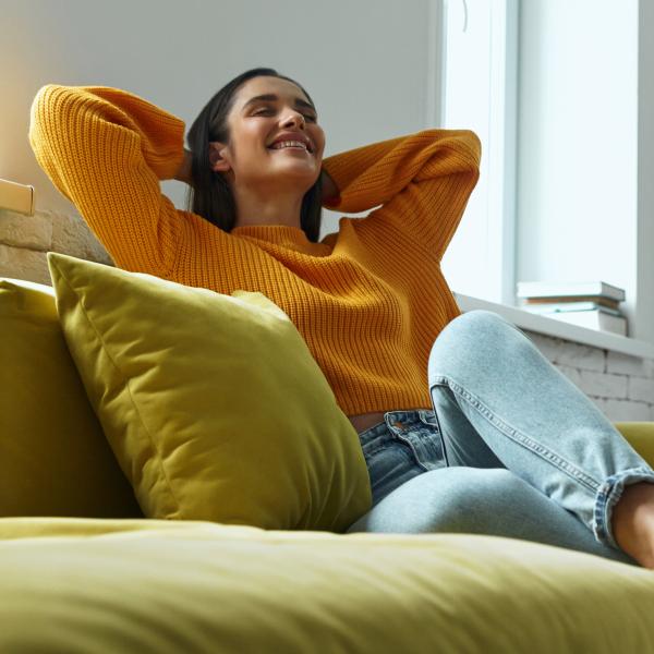 Femme heureuse les bras derrière la tête assise sur un canapé